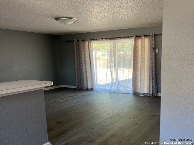 spare room featuring a textured ceiling and dark hardwood / wood-style floors