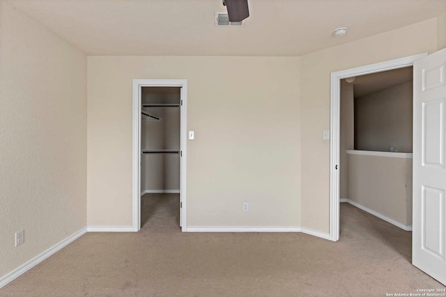 unfurnished bedroom featuring light colored carpet, ceiling fan, a spacious closet, and a closet