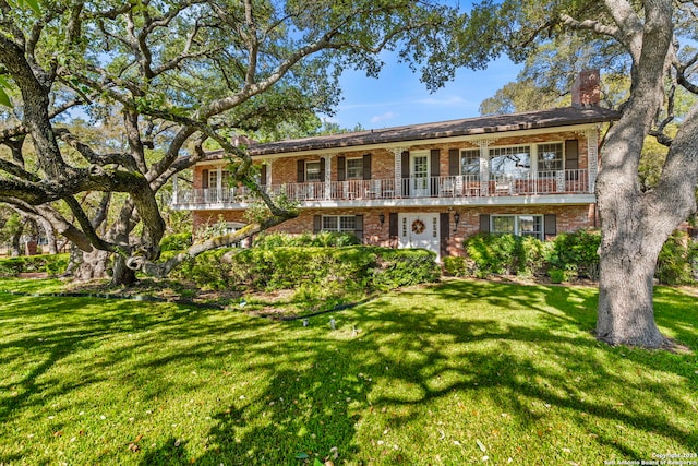 view of front of property featuring a balcony and a front lawn