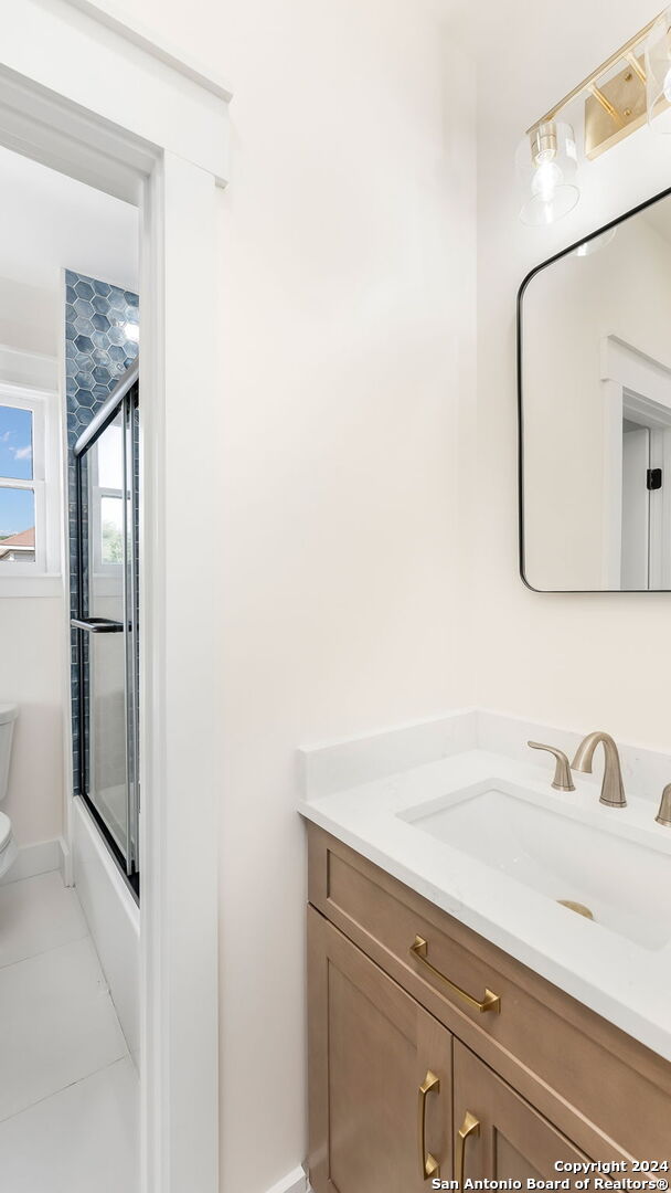 full bathroom with toilet, combined bath / shower with glass door, vanity, and tile patterned floors