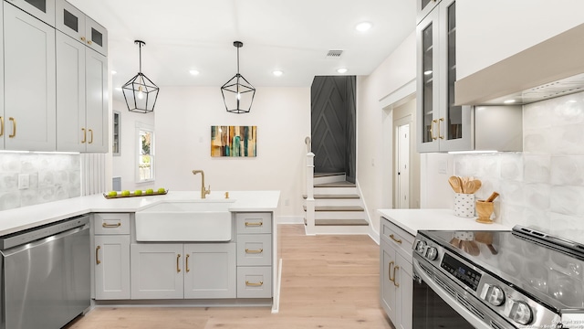 kitchen featuring tasteful backsplash, appliances with stainless steel finishes, sink, and light wood-type flooring