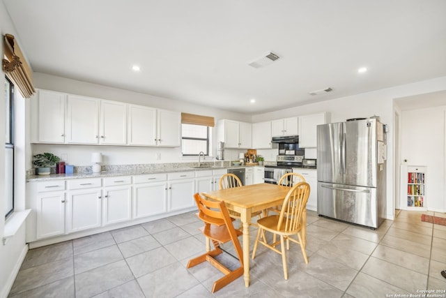 kitchen with appliances with stainless steel finishes, white cabinets, light stone countertops, and sink