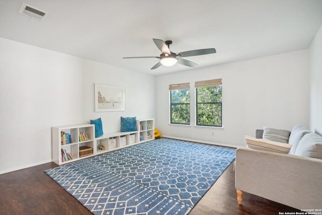 living area featuring dark wood-type flooring and ceiling fan