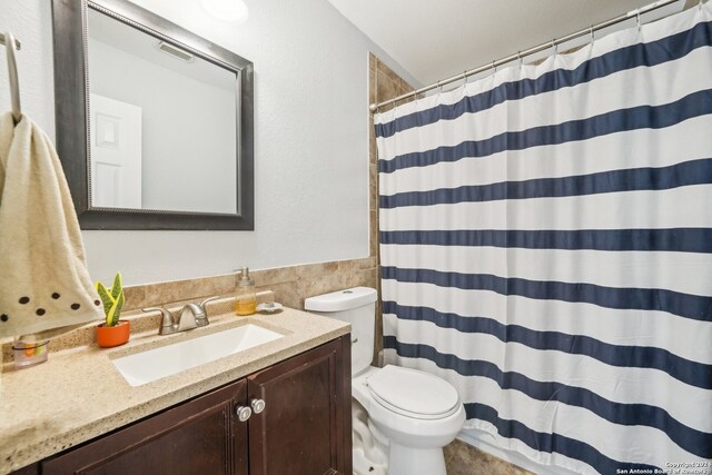 bathroom featuring vanity, toilet, and curtained shower