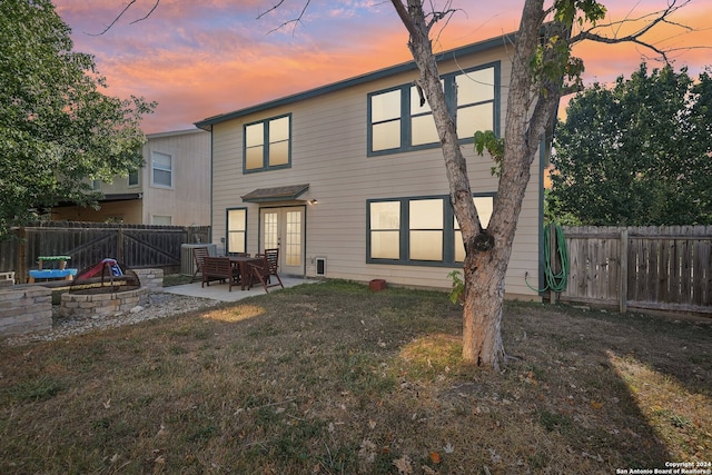 back house at dusk with a yard, an outdoor fire pit, and a patio area