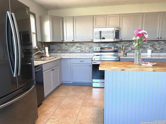 kitchen featuring wooden counters, tasteful backsplash, sink, black appliances, and gray cabinets