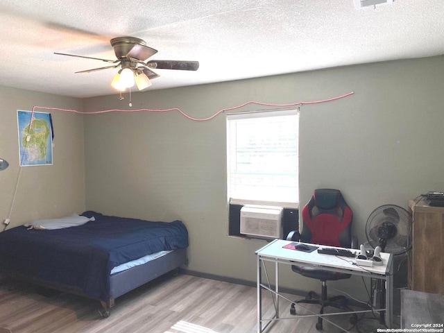 bedroom with ceiling fan, hardwood / wood-style floors, cooling unit, and a textured ceiling