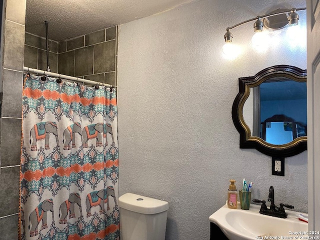 bathroom with a shower with curtain, a textured ceiling, toilet, and sink