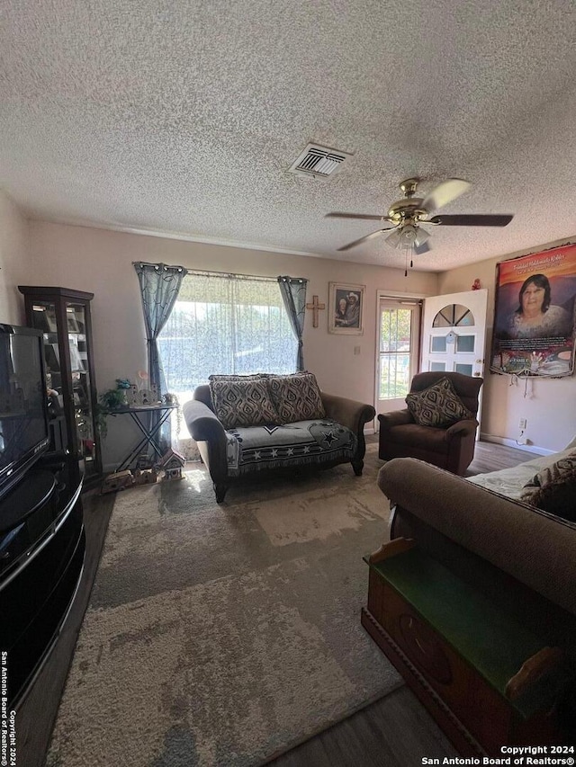 carpeted living room with a textured ceiling and ceiling fan