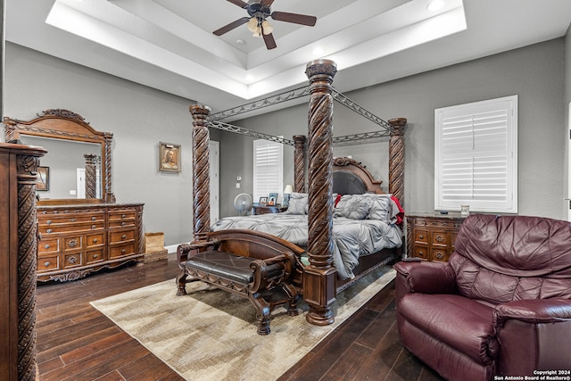 bedroom featuring dark wood-type flooring, a tray ceiling, and ceiling fan