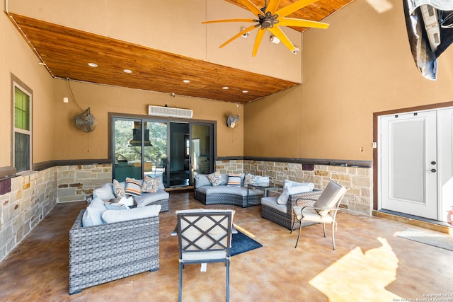 living room featuring tile walls, a high ceiling, ceiling fan, and wooden ceiling