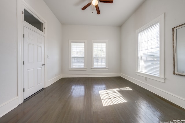 empty room with dark hardwood / wood-style floors, a healthy amount of sunlight, and ceiling fan