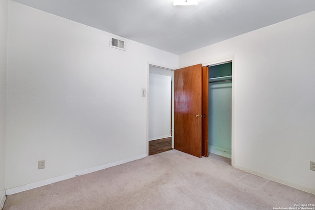 unfurnished bedroom featuring light carpet and a closet