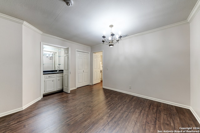 spare room featuring ornamental molding, dark wood-type flooring, a textured ceiling, and an inviting chandelier