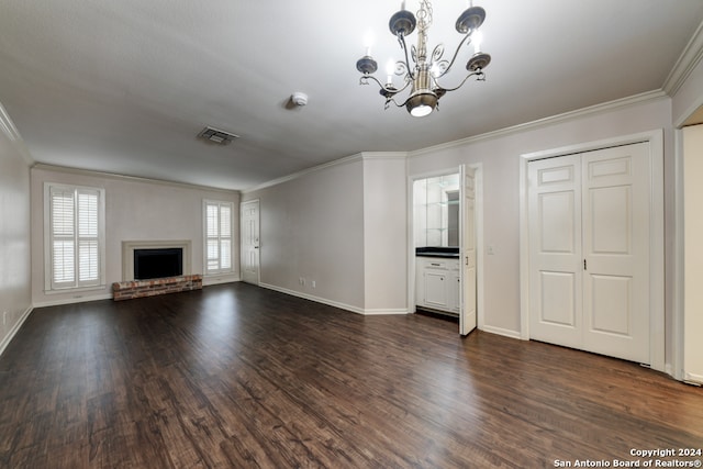 unfurnished living room with an inviting chandelier, a brick fireplace, crown molding, and dark hardwood / wood-style flooring