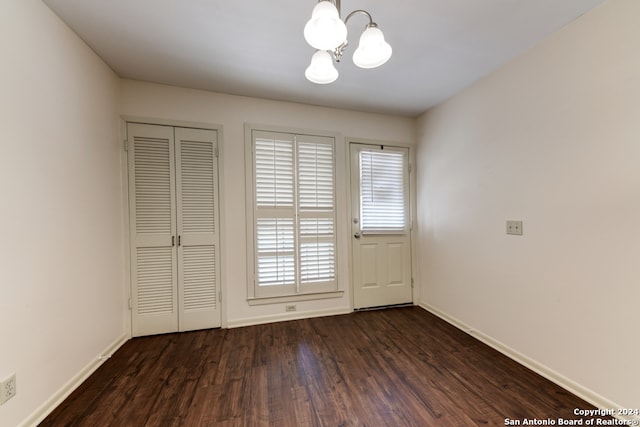 empty room with a chandelier and dark hardwood / wood-style flooring