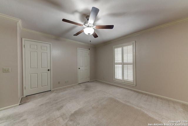 carpeted empty room with ceiling fan and crown molding