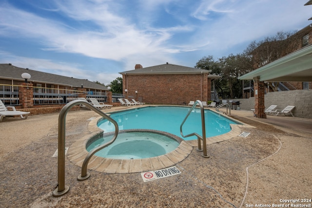 view of pool with a hot tub and a patio area