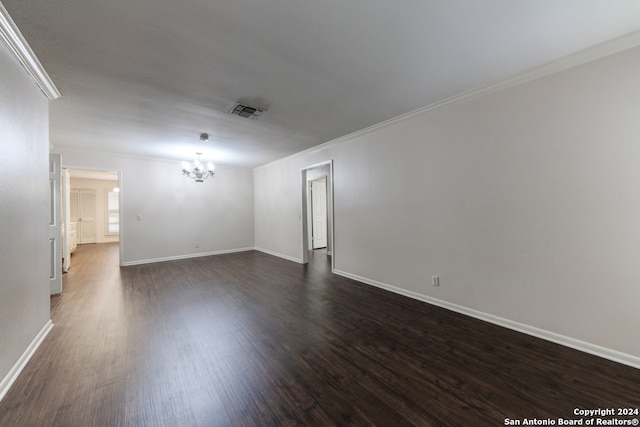 spare room featuring ornamental molding, dark hardwood / wood-style floors, and a chandelier