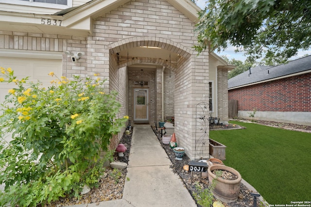 doorway to property featuring a garage and a lawn