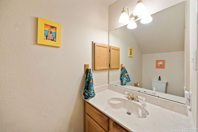 bathroom featuring toilet, lofted ceiling, vanity, and an inviting chandelier