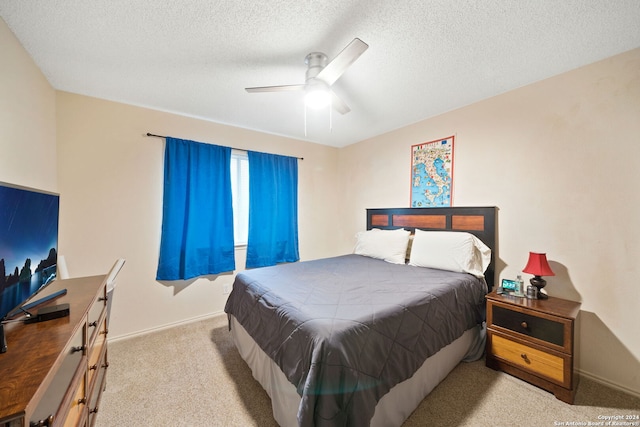 carpeted bedroom featuring ceiling fan and a textured ceiling