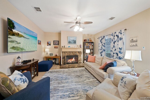 tiled living room with a fireplace and ceiling fan