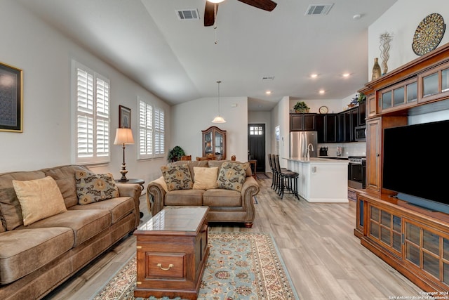 living room with light wood-type flooring, ceiling fan, and lofted ceiling