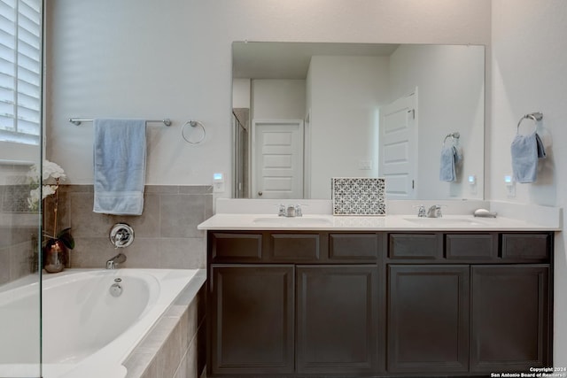 bathroom with vanity and tiled bath