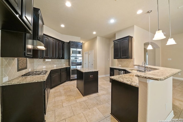 kitchen featuring appliances with stainless steel finishes, sink, a kitchen island, kitchen peninsula, and pendant lighting