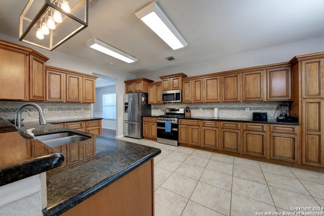 kitchen featuring dark stone countertops, stainless steel appliances, tasteful backsplash, and light tile patterned flooring