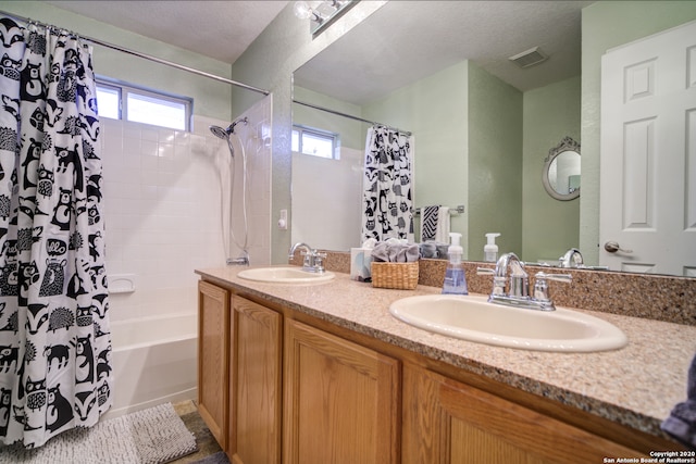 bathroom with vanity, a textured ceiling, a healthy amount of sunlight, and shower / bathtub combination with curtain