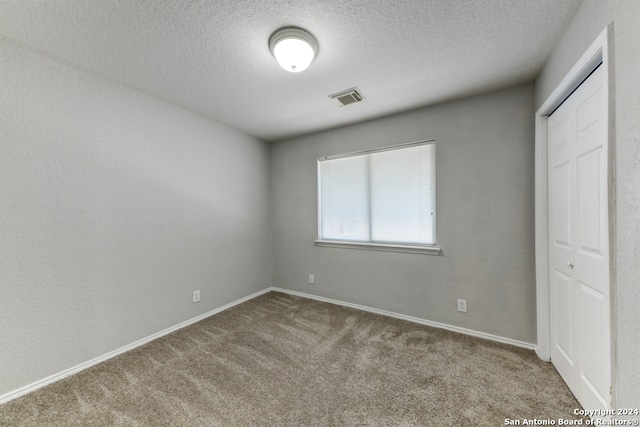 unfurnished bedroom featuring a closet, carpet, and a textured ceiling