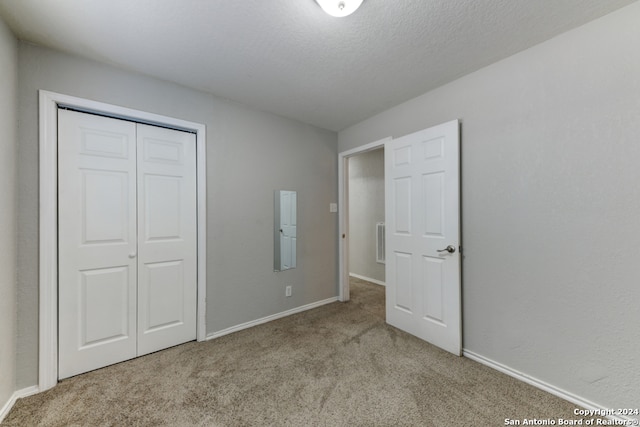 unfurnished bedroom with a closet, a textured ceiling, and light colored carpet