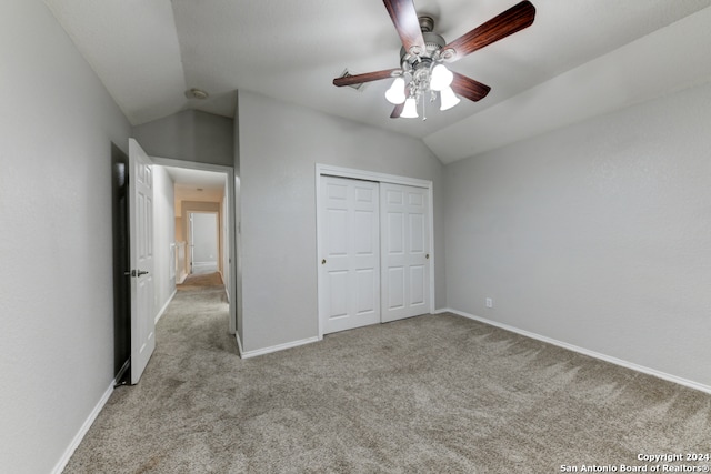 unfurnished bedroom with a closet, ceiling fan, light carpet, and vaulted ceiling