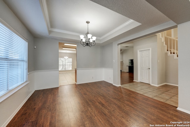 empty room featuring a notable chandelier, hardwood / wood-style floors, and a tray ceiling