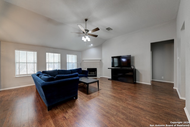 living room with lofted ceiling, dark wood-type flooring, a tile fireplace, and ceiling fan