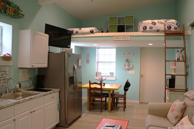 kitchen with lofted ceiling, stainless steel fridge with ice dispenser, white cabinetry, light wood-type flooring, and sink