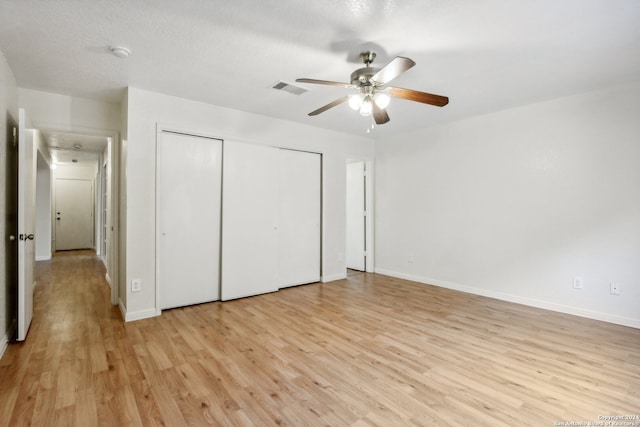 unfurnished bedroom featuring light hardwood / wood-style flooring, a textured ceiling, a closet, and ceiling fan