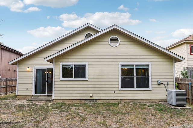 rear view of property featuring cooling unit and a lawn