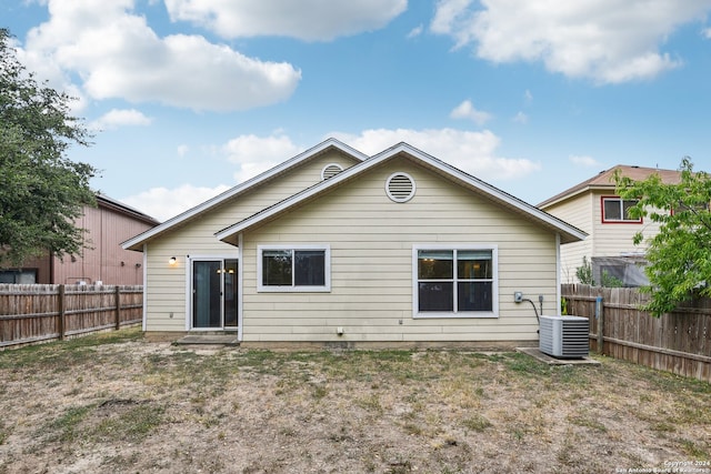 back of house with central AC unit and a lawn