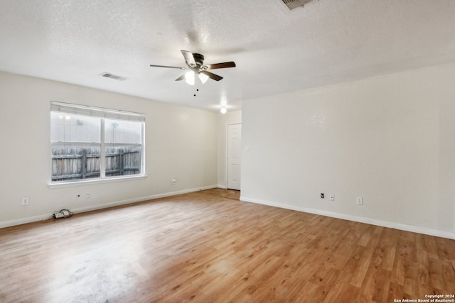 unfurnished room with a textured ceiling, light wood-type flooring, and ceiling fan