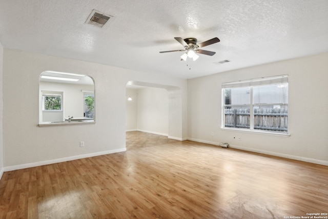 empty room with light hardwood / wood-style floors, a textured ceiling, and ceiling fan