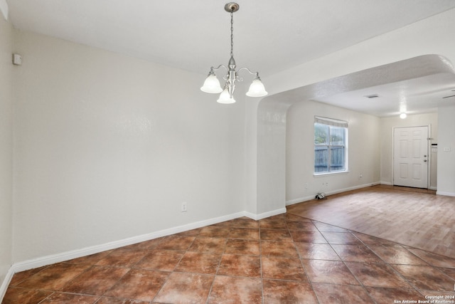 unfurnished room featuring a chandelier and dark wood-type flooring