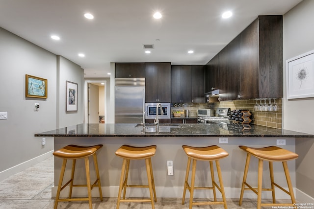 kitchen with a breakfast bar area, stainless steel appliances, kitchen peninsula, and sink