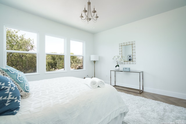 bedroom featuring parquet flooring, multiple windows, and an inviting chandelier