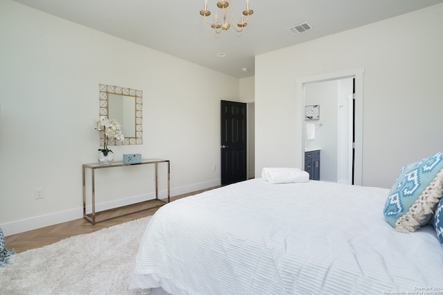 bedroom with connected bathroom, parquet flooring, and an inviting chandelier