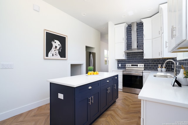 kitchen featuring wall chimney exhaust hood, stainless steel appliances, sink, a center island, and white cabinets