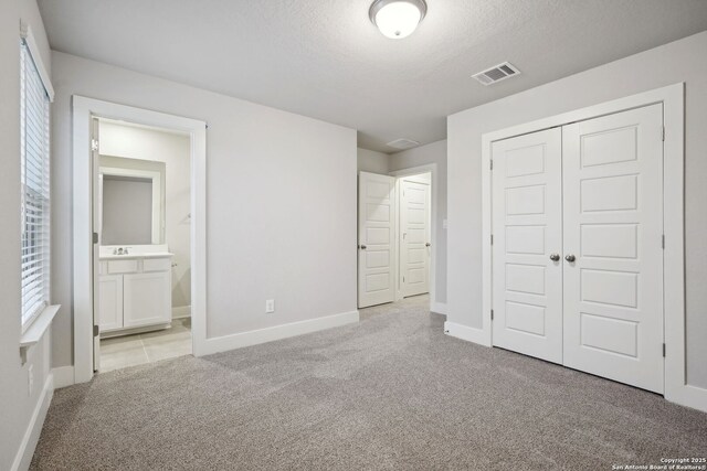 1327 Larkspur Pass, San Antonio, TX 78245 - unfurnished bedroom featuring light carpet, a closet, a textured ceiling, and ensuite bathroom
