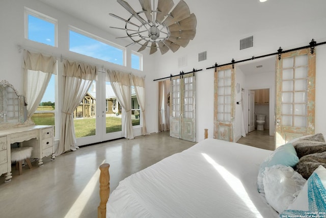 bedroom with ceiling fan, access to outside, a barn door, connected bathroom, and a high ceiling